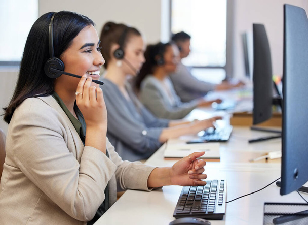 We take care of our customers. a young call centre agent working in an office with her colleagues in the background - Foto, Imagen