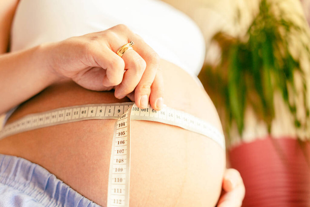Medir el vientre de la mujer embarazo. Feliz joven embarazada con cinta métrica del vientre. Concepto maternidad, embarazo, parto - Foto, imagen