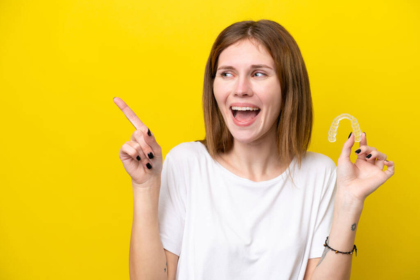 Young English woman holding invisible braces intending to realizes the solution while lifting a finger up - Foto, Bild