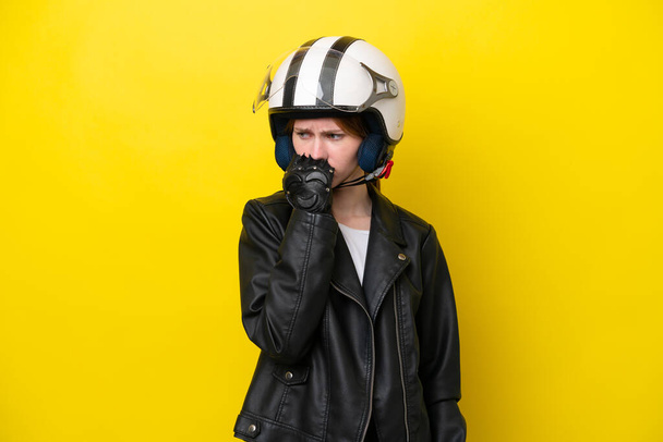 Giovane donna inglese con un casco moto isolato su sfondo giallo avendo dubbi - Foto, immagini