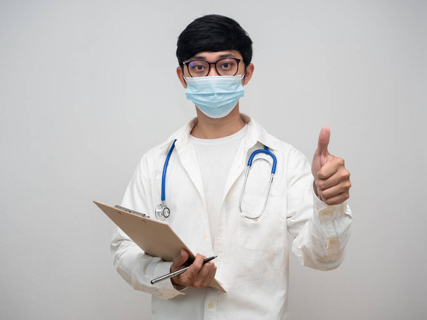 Jóképű orvos visel orvosi maszk hold ellenőrző lista fórumon hüvelykujj fel portré - Fotó, kép
