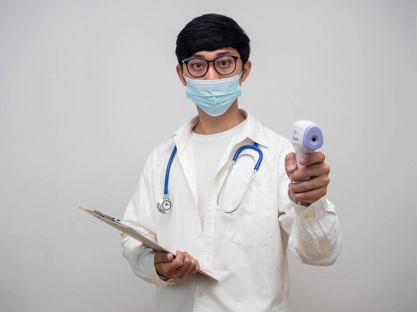 Портрет доктора в медицинской маске держать инфракрасный термометр с цыплятами список борту - Фото, изображение