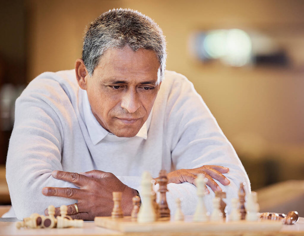 My opponent is really good. a mature man sitting alone inside and looking contemplative while playing a game of chess - Foto, Bild