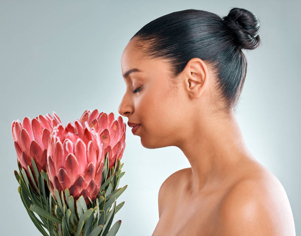 Smells so beautiful, smells like me. Studio shot of an attractive young woman smelling protea flowers against a grey background - Foto, Bild