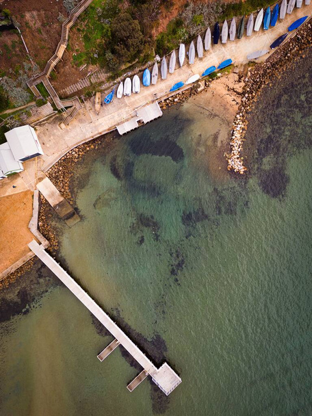 A pier over the sea with canoes on the shore from a bird's eye view - Foto, imagen