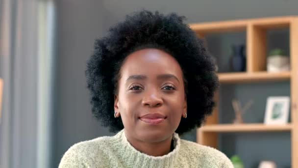 Portrait of happy african woman smiling at home inside her living room. Face of a young female with afro looking relaxed and comfortable on a weekend morning, enjoying alone time in cozy winter. - Video