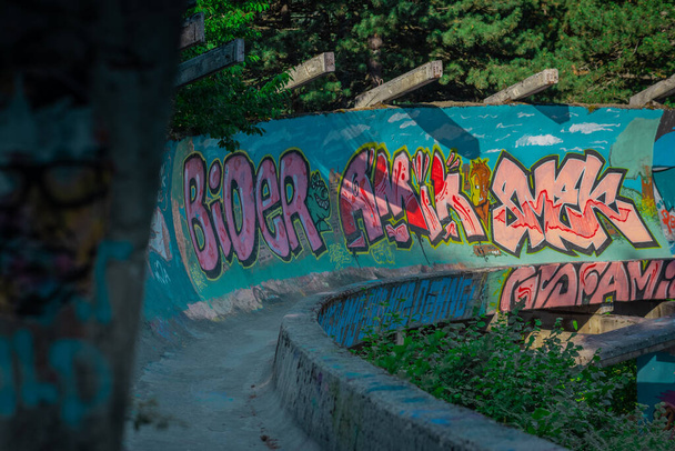 SARAJEVO,  BOSNIA, 11.7..2022: Abandoned or deserted remains of former olympic bobsleigh track in Sarajevo, for the 1984 winter olympics. - Fotó, kép