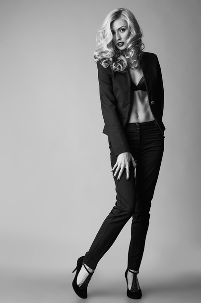 junge blonde sexy Frau im Business-Anzug auf grauem Hintergrund.  - Foto, Bild