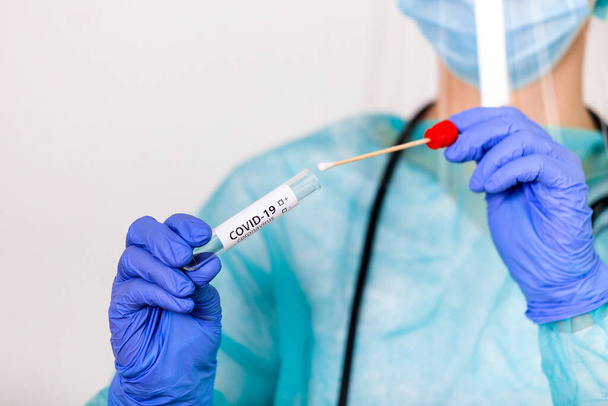 Technicien de laboratoire tenant un kit de prélèvement d'écouvillonnage, équipement de prélèvement d'échantillons de Coronavirus COVID-19, prélèvement nasal et oral d'ADN pour PCR procédure d'essai en chaîne de réaction de polymérase et expédition - Photo, image