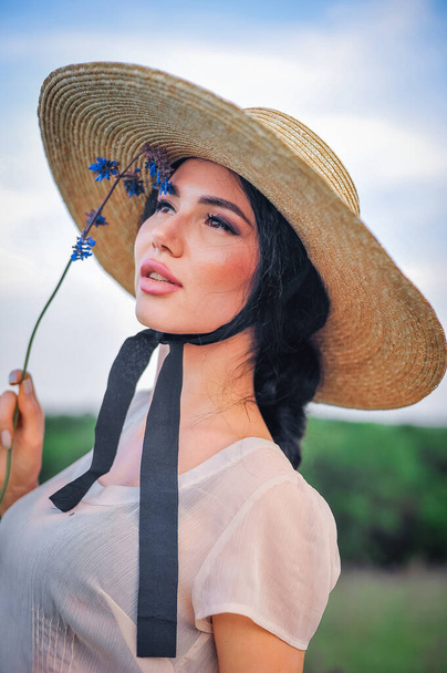 beautiful young woman in a hat and a straw dress on a field - Photo, Image