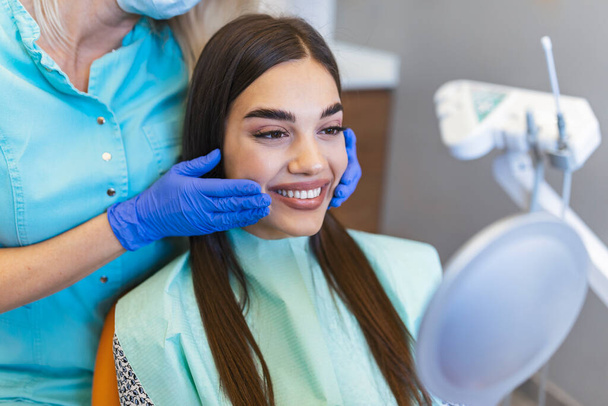 Woman looks in the mirror in dentist chair.Viewed oral hygiene. Woman at the dentist. Woman in the dental chair dental treatment during surgery. - Photo, Image