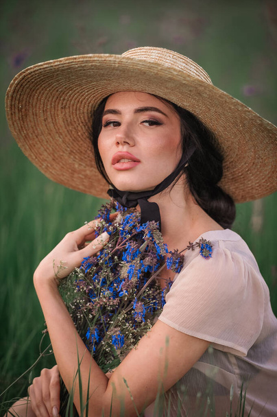 beautiful young woman in a hat and a straw dress in a field - Photo, Image