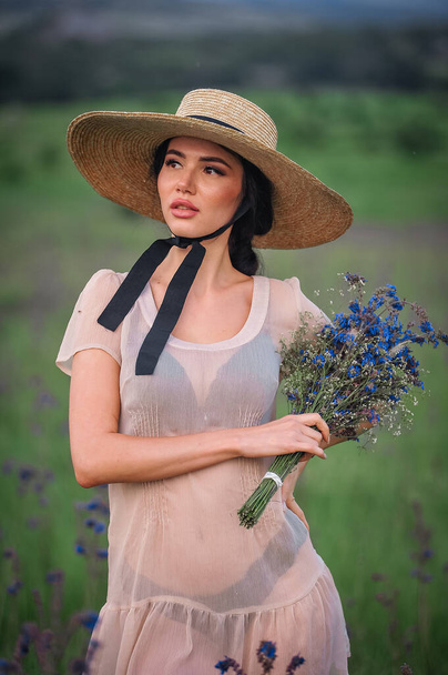 Şapkalı güzel genç bir kadın ve çiçekli beyaz bir elbise. - Fotoğraf, Görsel