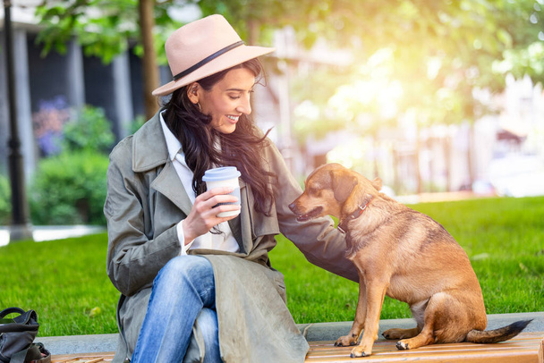 Beautiful young woman playing with her dogin a park outdoors. Lifestyle portrait. Cute young woman hugs her puppy dog. Love between owner and dog. - Φωτογραφία, εικόνα