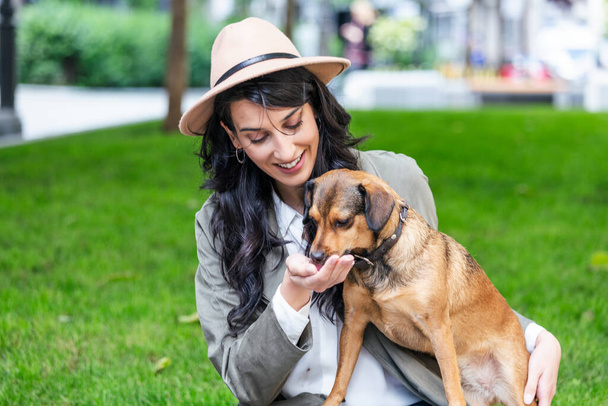 happy hipster woman playing with her dog and drinking coffee. stylish girl with funny dog resting, hugging and having fun in sun, cute moments. space for text - Foto, immagini