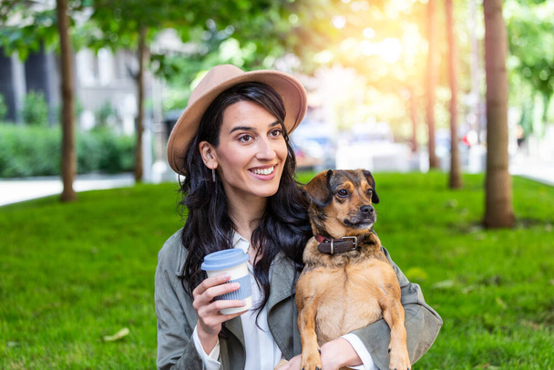Beautiful young woman playing with her dogin a park outdoors. Lifestyle portrait. Cute young woman hugs her puppy dog. Love between owner and dog. - Foto, imagen
