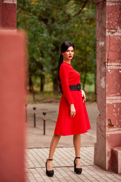 beautiful young woman in a red dress and a black skirt on a background of a street - Фото, изображение