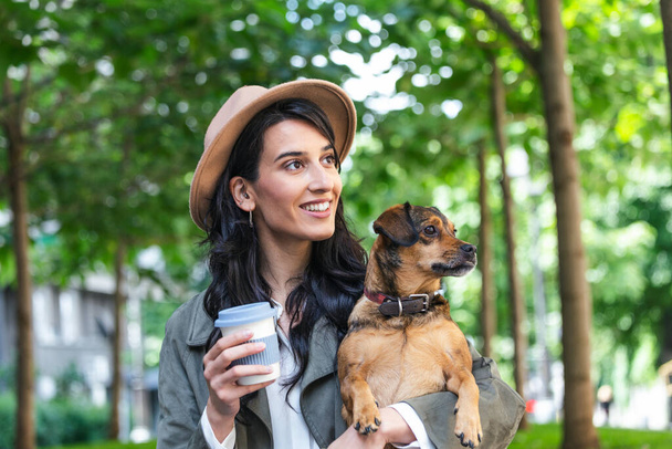 happy hipster woman playing with her dog and drinking coffee. stylish girl with funny dog resting, hugging and having fun in sun, cute moments. space for text - Fotoğraf, Görsel