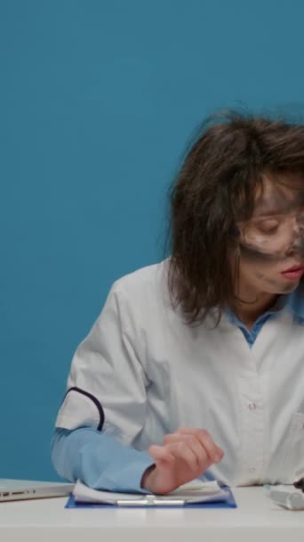 Vertical video: Insane goofy scientist using micro pipette and test tube in front of camera, acting crazy in studio and doing foolish silly facial expressions. Amusing funny female chemist with dirty - 映像、動画