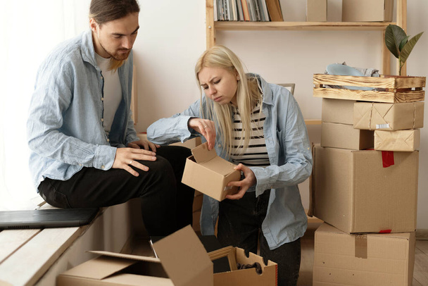 Unhappy woman client dissatisfied by parcel, looking in open cardboard damaged box, crushed fragile goods, bad delivery service concept. - Фото, изображение