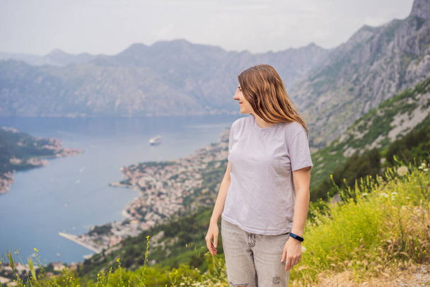 Woman tourist enjoys the view of Kotor. Montenegro. Bay of Kotor, Gulf of Kotor, Boka Kotorska and walled old city. Travel to Montenegro concept. Fortifications of Kotor is on UNESCO World Heritage. - Zdjęcie, obraz