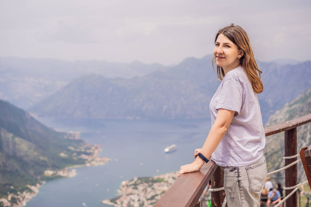 Woman tourist enjoys the view of Kotor. Montenegro. Bay of Kotor, Gulf of Kotor, Boka Kotorska and walled old city. Travel to Montenegro concept. Fortifications of Kotor is on UNESCO World Heritage. - Fotografie, Obrázek