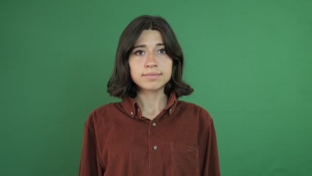 Angry facial expression using hands, young woman with angry facial expression, facial expression of young woman in front of green curtain - Imágenes, Vídeo
