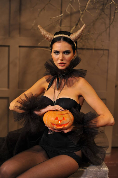 beautiful young witch with halloween pumpkin and lantern on her face - Foto, immagini