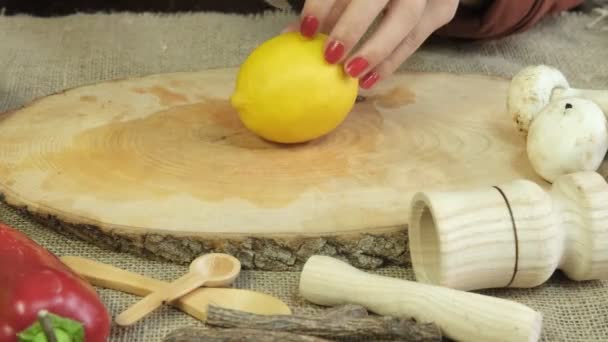 Vrouw snijdt citroen met mes, snijproces op houten presentatieplaat, snijdt gele citroenen in tweeën met een mes op tien houten snijplanken - Video