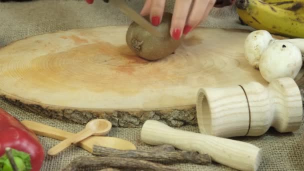Cutting kiwi slices with knife, image of slicing green kiwis on wooden presentation board, woman hand chopping round kiwi close-up, preparing thematic fresh fruit - Filmagem, Vídeo