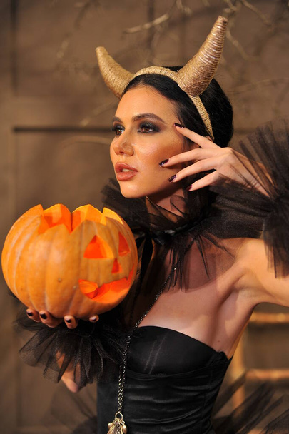 beautiful young woman with halloween pumpkin in her hands - 写真・画像