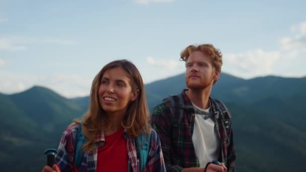 Smiling couple hiking summer mountains closeup. Young travelers explore nature close up. Active tourists wear backpacks on family holiday. Excited friends walk trekking trail together. Travel concept. - Filmagem, Vídeo