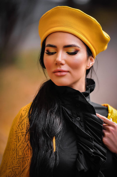 Porträt einer schönen jungen Frau in gelber Jacke und Schal vor Herbstblättern - Foto, Bild