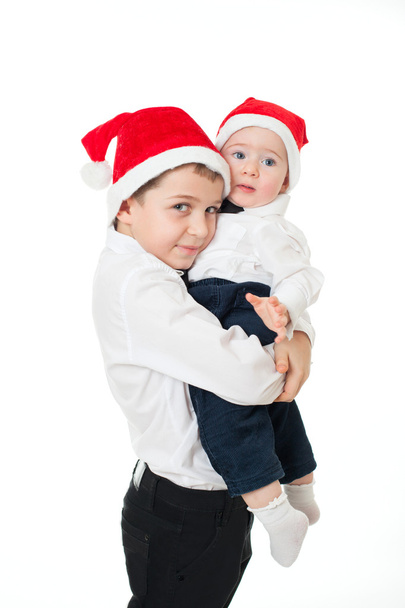 Boys brothers in santa's hats hugging - 写真・画像