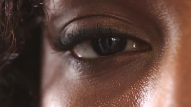 Nahaufnahme des Auges einer Frau mit einem intensiven Blick, die blinzelt, während sie konzentriert auf eine Augenuntersuchung blickt. Gesicht einer ernsten afrikanischen Frau, die sich wach und bewusst fühlt, während sie ihr Sehvermögen und ihre Sehkraft testet. - Filmmaterial, Video