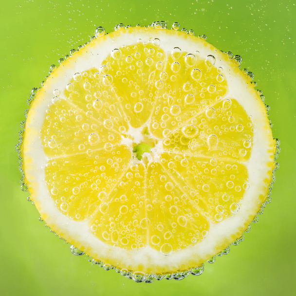 Fresh lemon in soda water covered with bubbles - Photo, Image