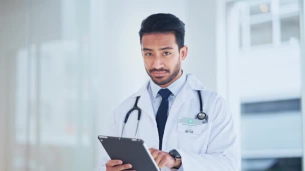A successful male doctor sending a prescription using the internet on a tablet inside a hospital. Portrait of a happy healthcare professional using telemedicine. GP smiling using a digital device. - Materiaali, video