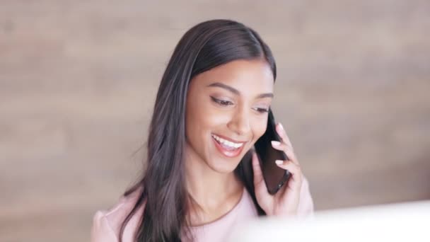 Cheerful young receptionist scheduling appointments and confirming meetings with clients in an office. Secretary talking on a phone while working on a computer at a front desk - Footage, Video