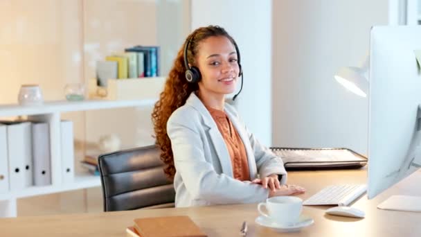 Young woman typing on computer and smiling in office using headset. Neat professional workspace indoors. Female could be accountant, researcher or lawyer that has received good news. - Séquence, vidéo