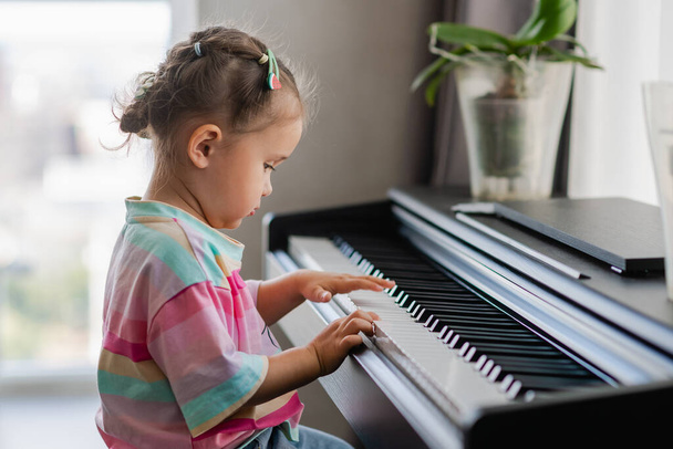 Cute little girl playing piano at a music school. Preschool child learning to play music instrument. Education, skills concept. - Φωτογραφία, εικόνα
