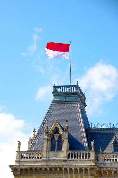 zászló lengyel egy sötét színű manzárd, a háttérben a kék ég néhány fehér felhők - Fotó, kép