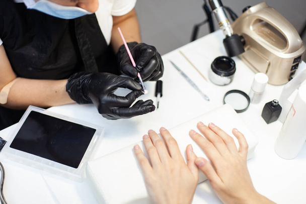 Manicurist glue false nails to a woman client in a nail salon. The working process - Fotografie, Obrázek