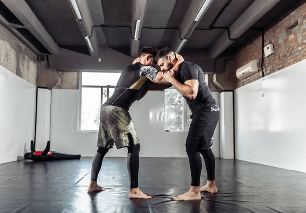 Sparring trénink dvou atletických MMA bojovníků v tělocvičně. Bojová umění, wrestling - Fotografie, Obrázek