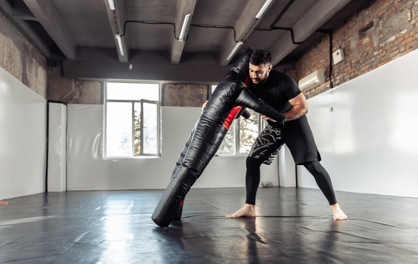 Atlético luchador masculino practicando sostiene con maniquí en el gimnasio - Foto, Imagen