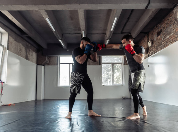 Egy bokszkesztyűs bokszoló két bokszoló partnere rugdos egy sportcsarnokban. - Fotó, kép