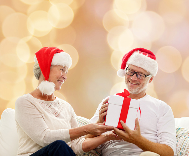glückliches Seniorenpaar in Weihnachtsmützen mit Geschenkbox - Foto, Bild