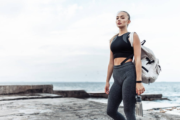 Portrait of young fit woman in sportswear on urban beach - Фото, изображение