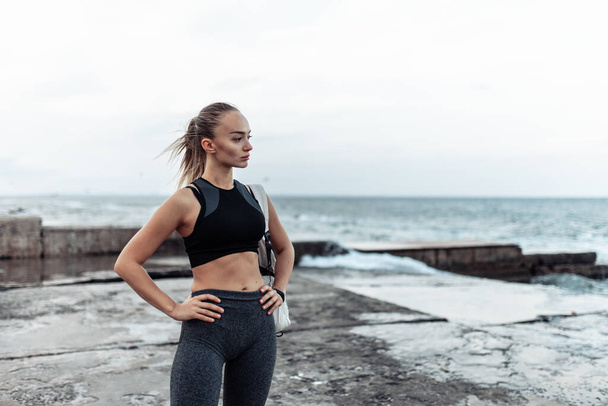 Portrait of young fit woman in sportswear on urban beach - Photo, Image