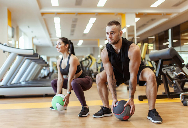 Αθλητικός άνδρας και γυναίκα προπονούνται μαζί με ιατρική μπάλα στο σύγχρονο γυμναστήριο. Υγιής τρόπος ζωής - Φωτογραφία, εικόνα