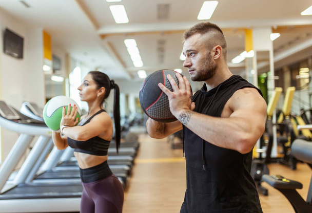 Athletic man and woman are training together with medicine ball in modern gym. Healthy lifestyle - Foto, Imagem